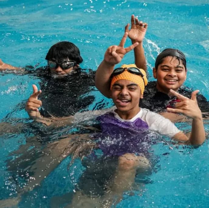 Three young MS YTCA swimmers smiling in the pool during a session